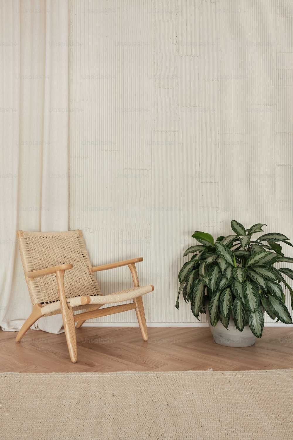 uma cadeira ao lado de um vaso de planta em um piso de madeira