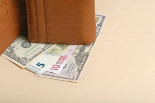 a brown wallet sitting on top of a pile of money