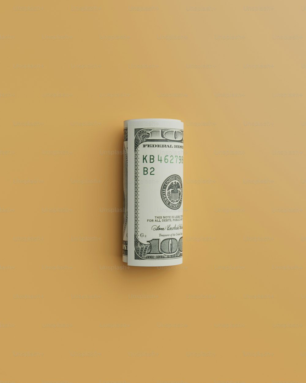 a roll of one hundred dollar bills on a yellow background