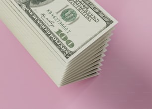uma pilha de notas de vinte dólares em um fundo rosa