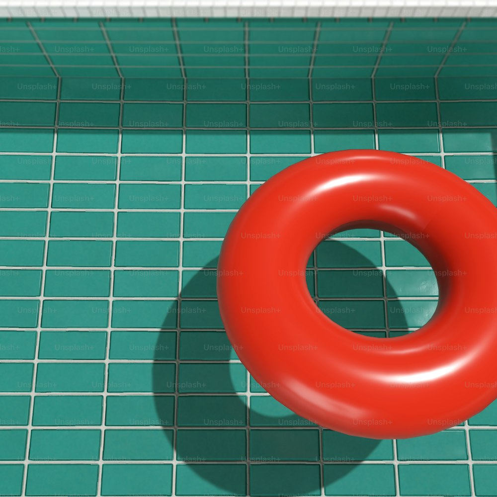 um anel vermelho sentado em cima de um piso de azulejos verdes