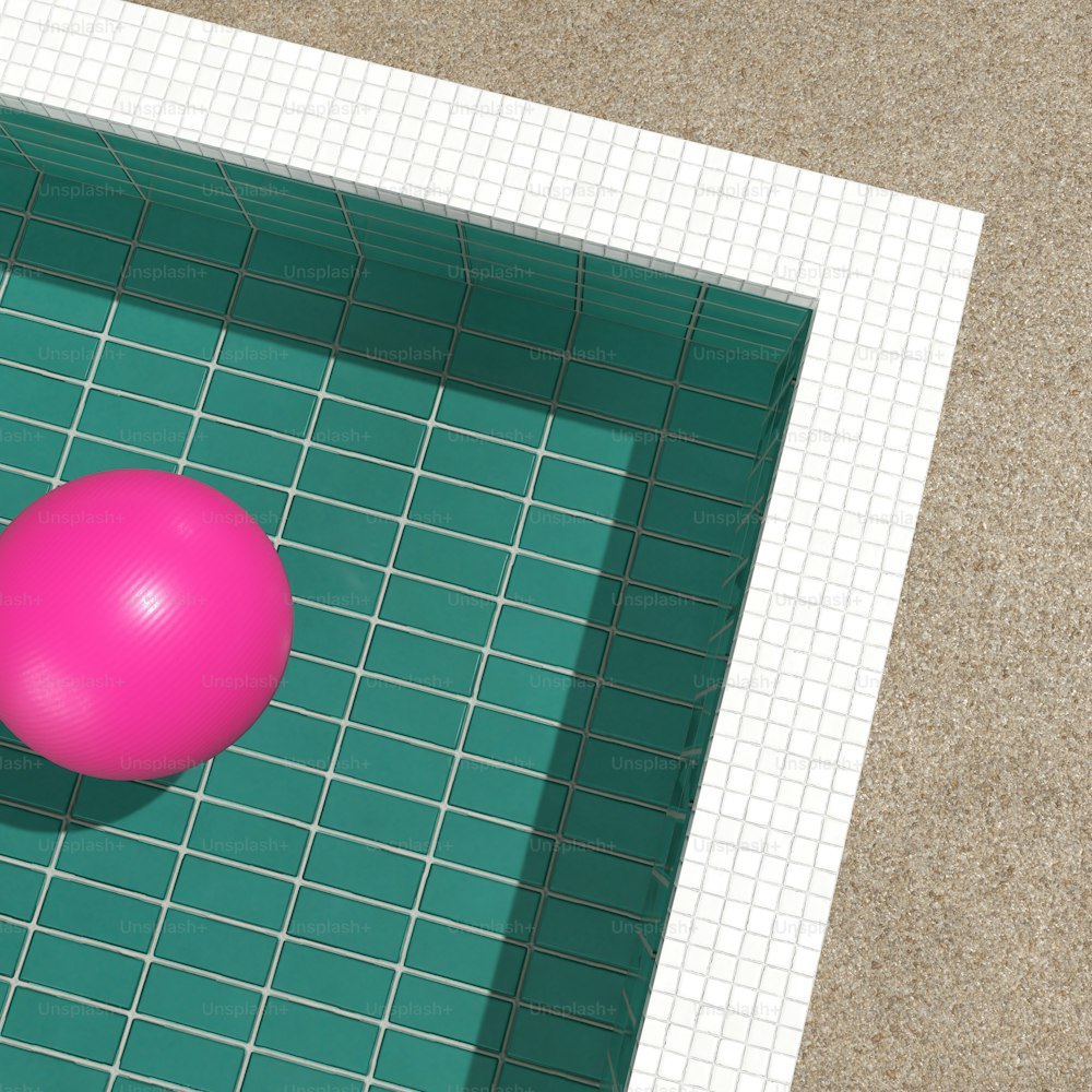 une boule rose posée sur un sol carrelé vert