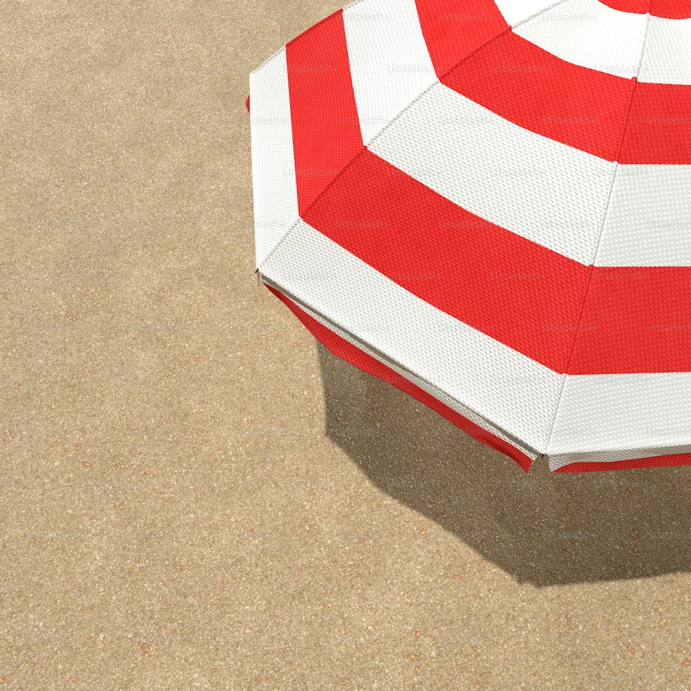 um guarda-sol vermelho e branco sentado em cima de uma praia de areia