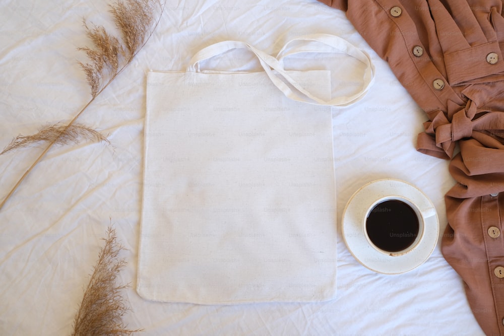 a cup of coffee and a tote bag on a bed