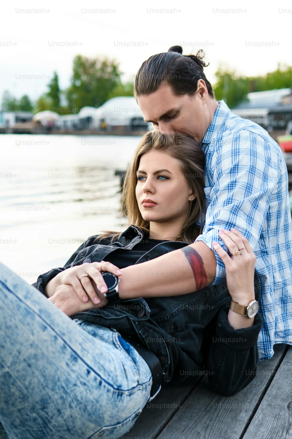 Portrait of young sensual and loving couple sitting on a pier beside a river