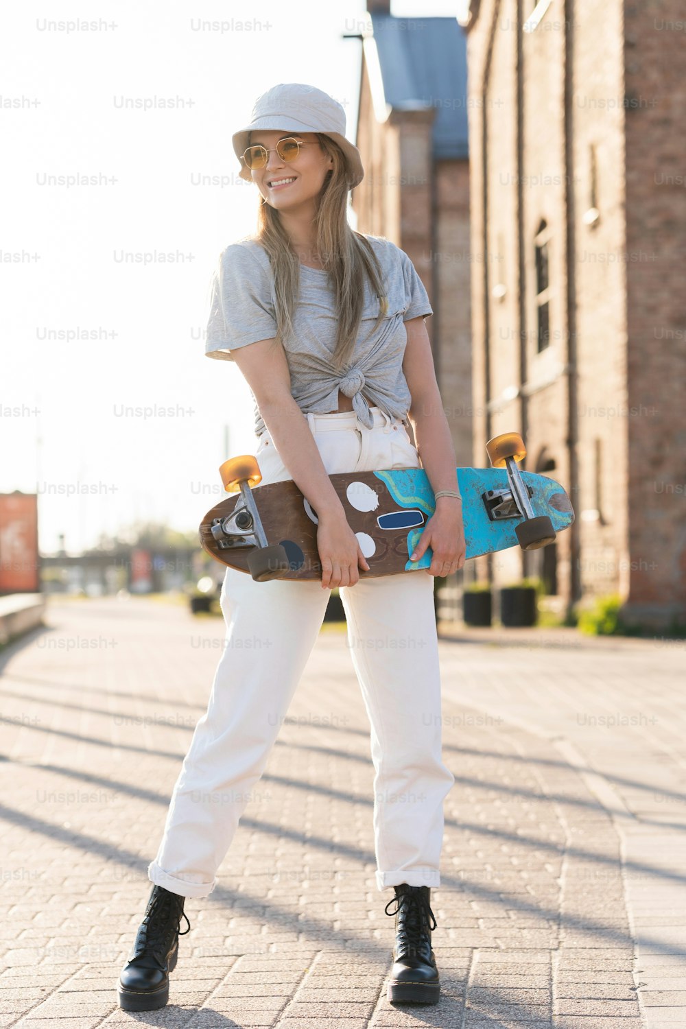 都市でロングボードを持つ若いスタイリッシュな女の子のポートレート
