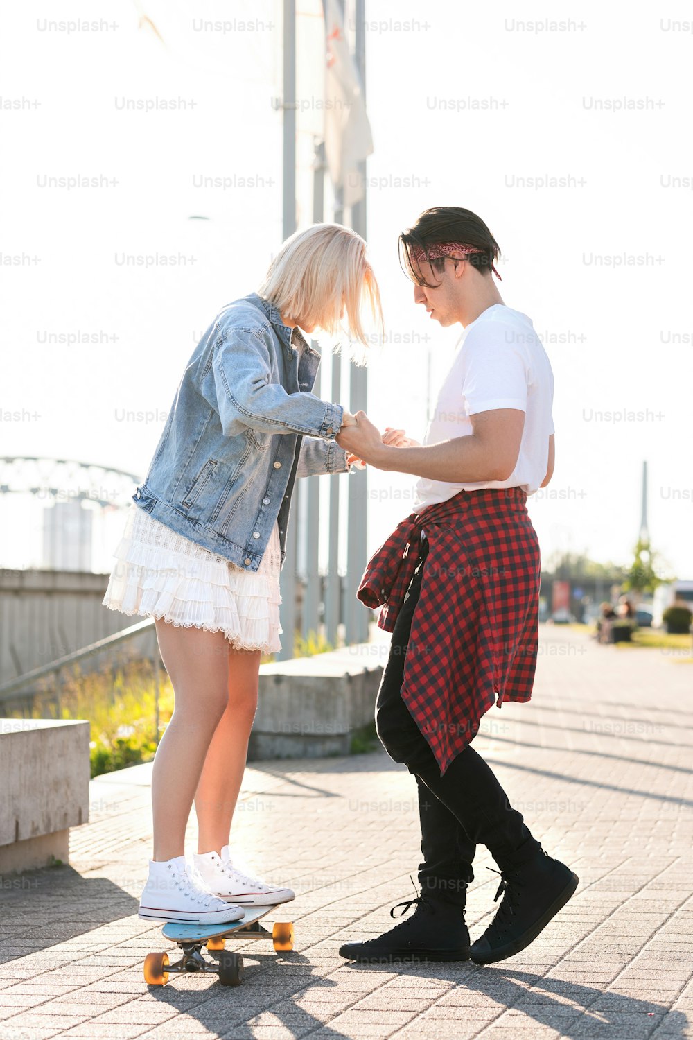 Stylish teenage couple riding longboard during their date in a city
