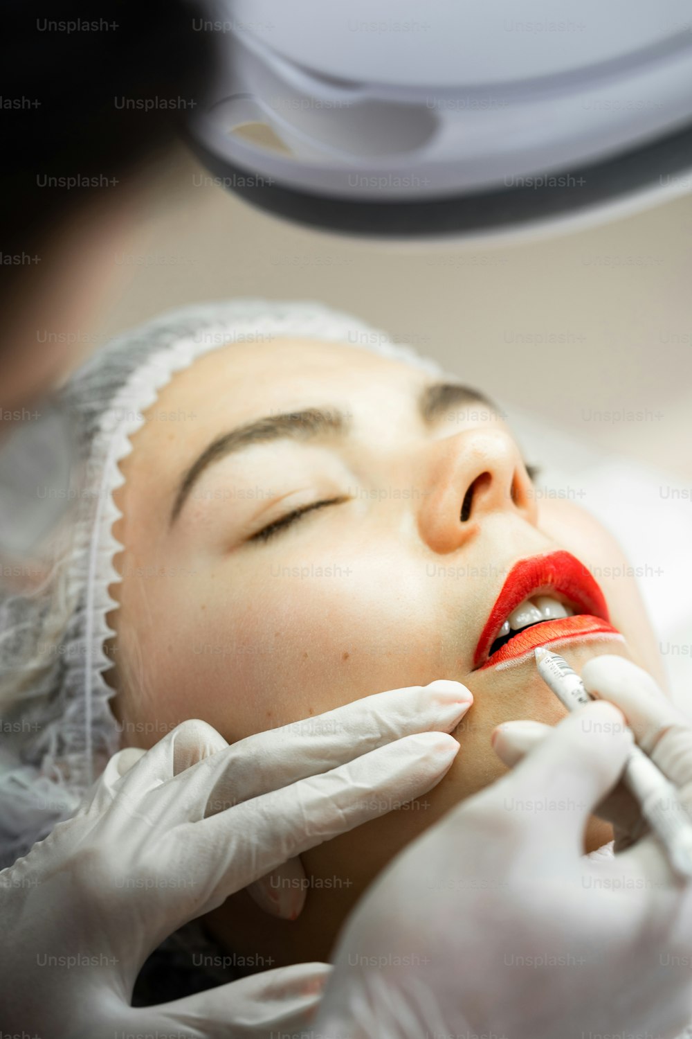 Professional permanent make-up artist and her client during lip blushing procedure