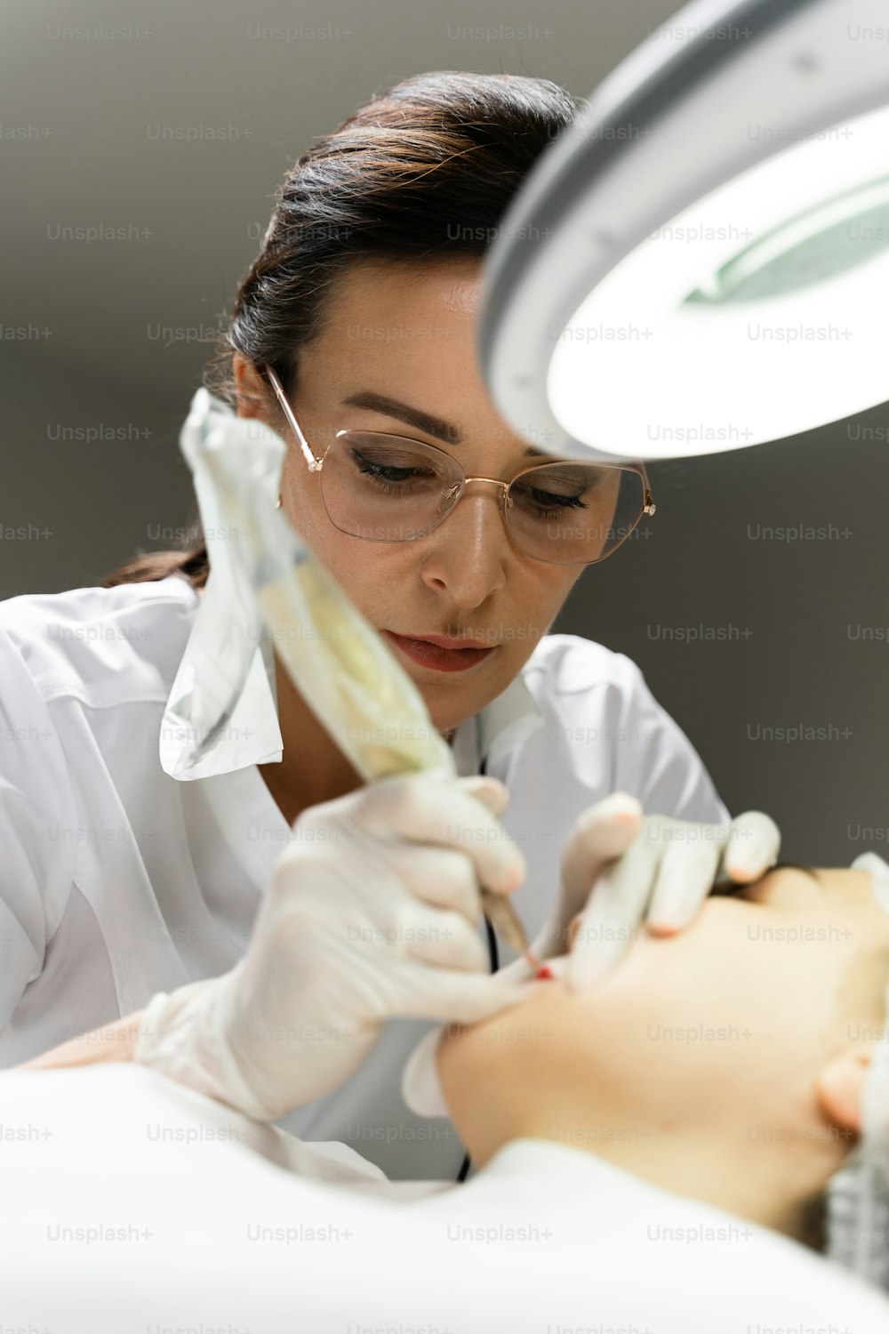 Professional permanent make-up artist and her client during lip blushing procedure