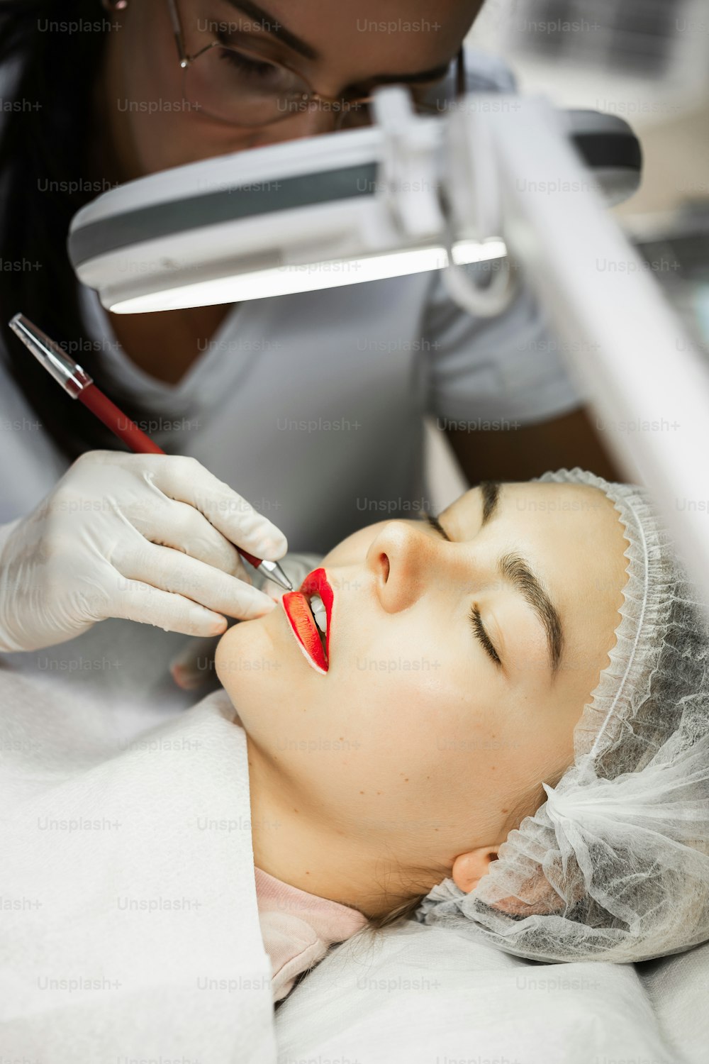 Professionelle Permanent Make-up Artistin und ihre Kundin während des Lippenerrötens