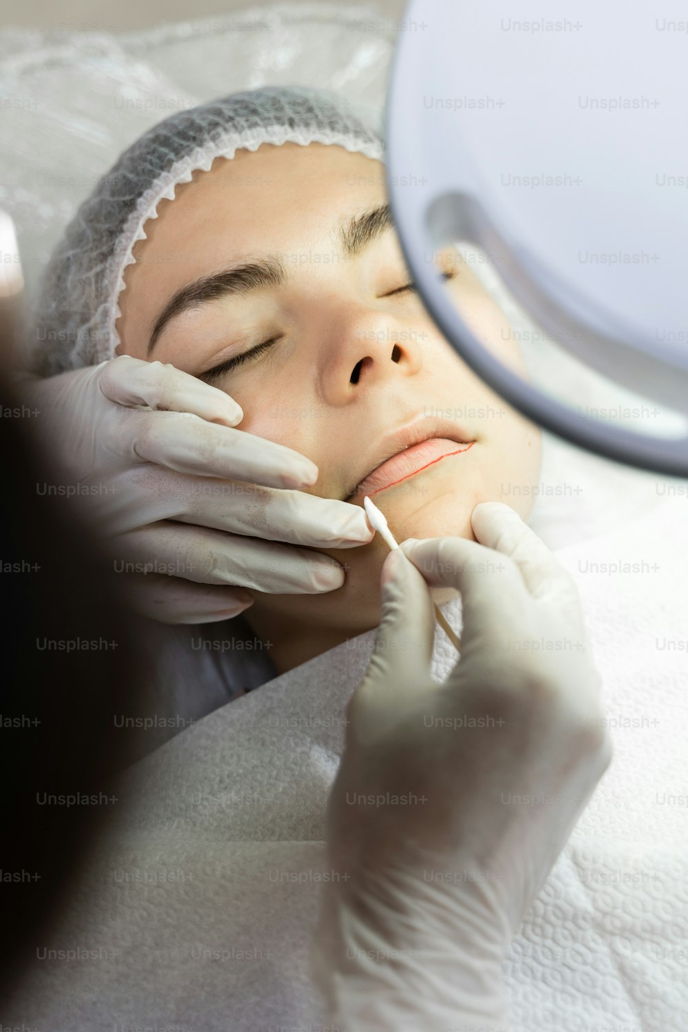 Truccatrice permanente professionista e la sua cliente durante la procedura di arrossamento delle labbra