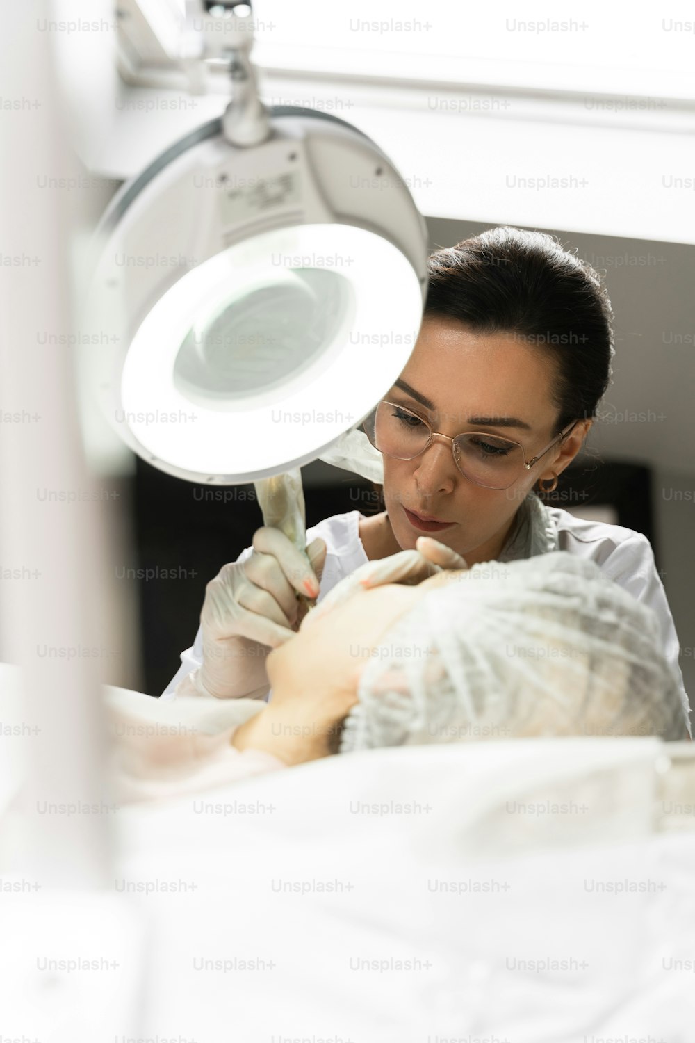 Professional permanent make-up artist and her client during lip blushing procedure