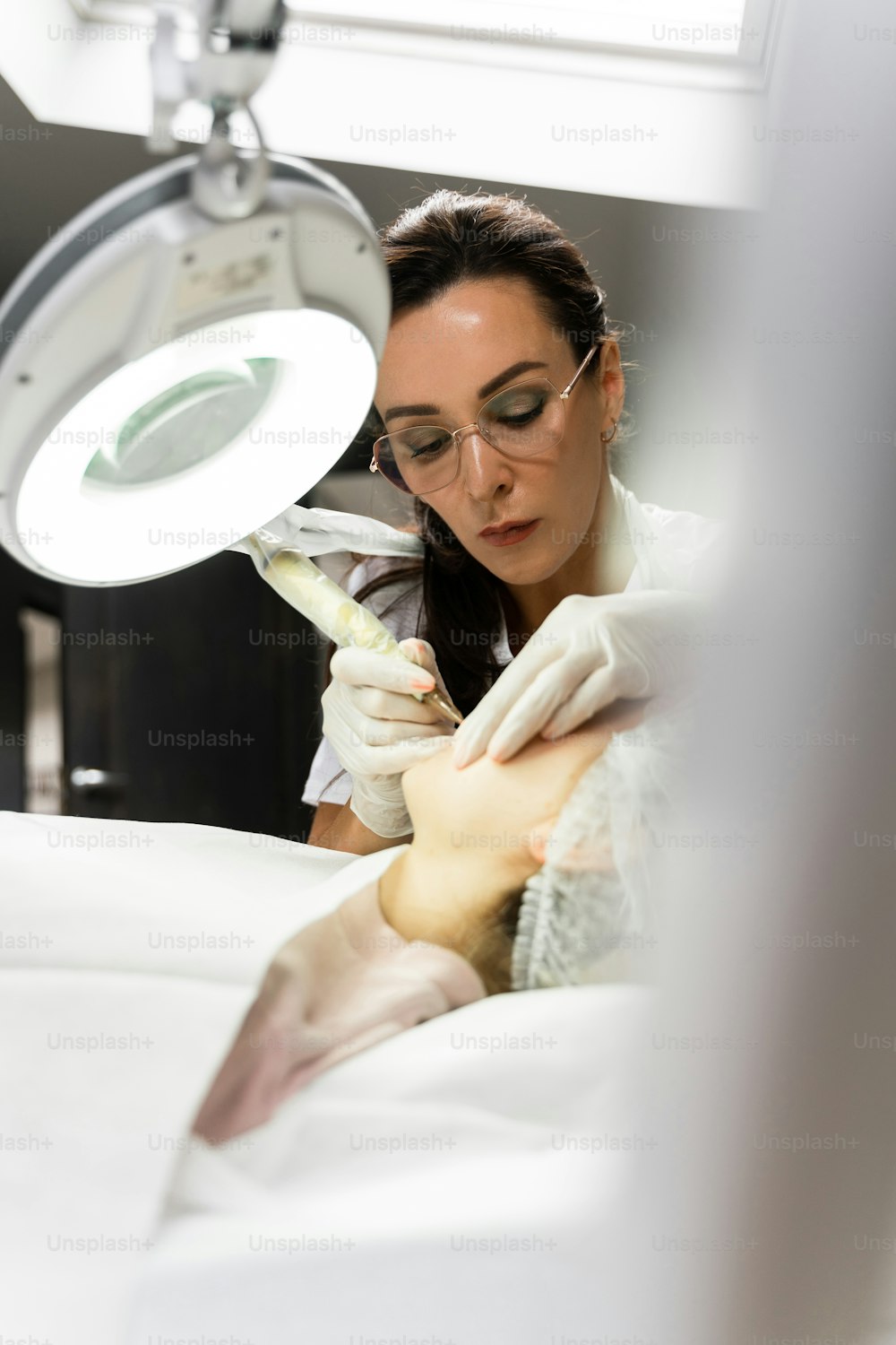Maquiadora permanente profissional e sua cliente durante o procedimento de rubor labial