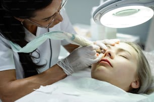 Professional permanent make-up artist and her client during lash line enhancement treatment