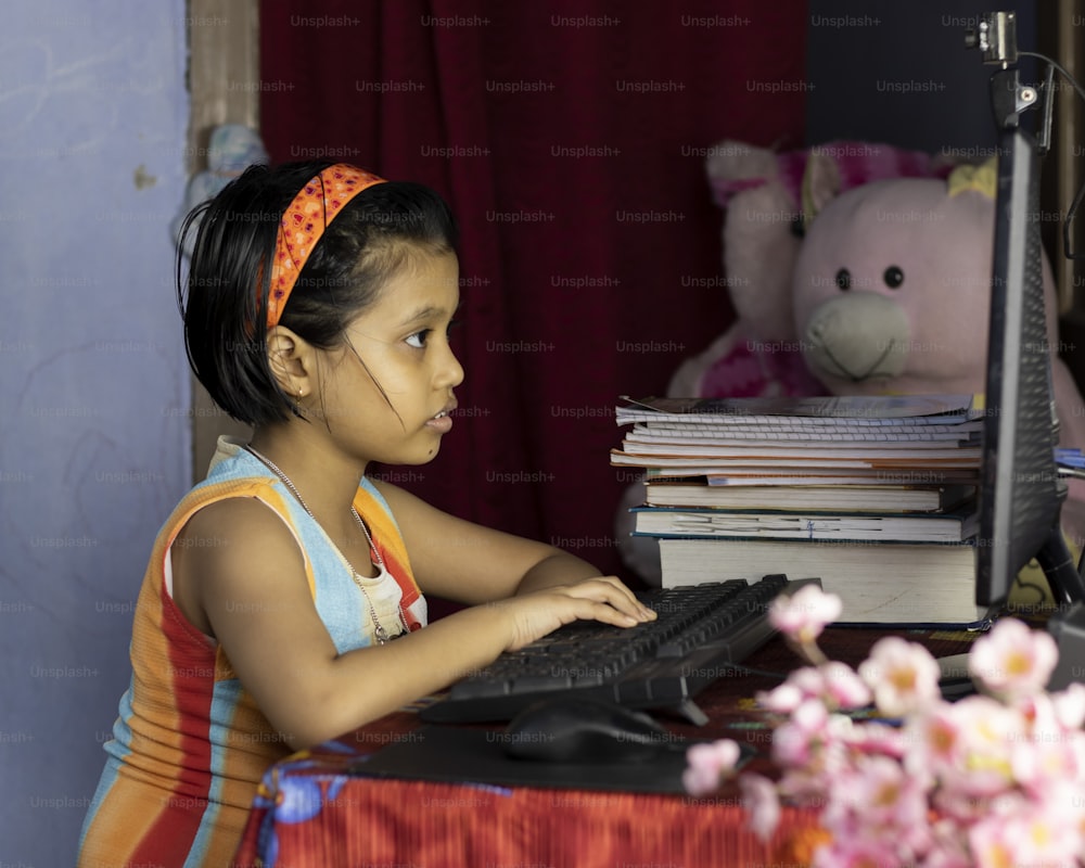 an Indian girl child with intense face attending online class on desktop computer during COVID-19 pandemic outbreak