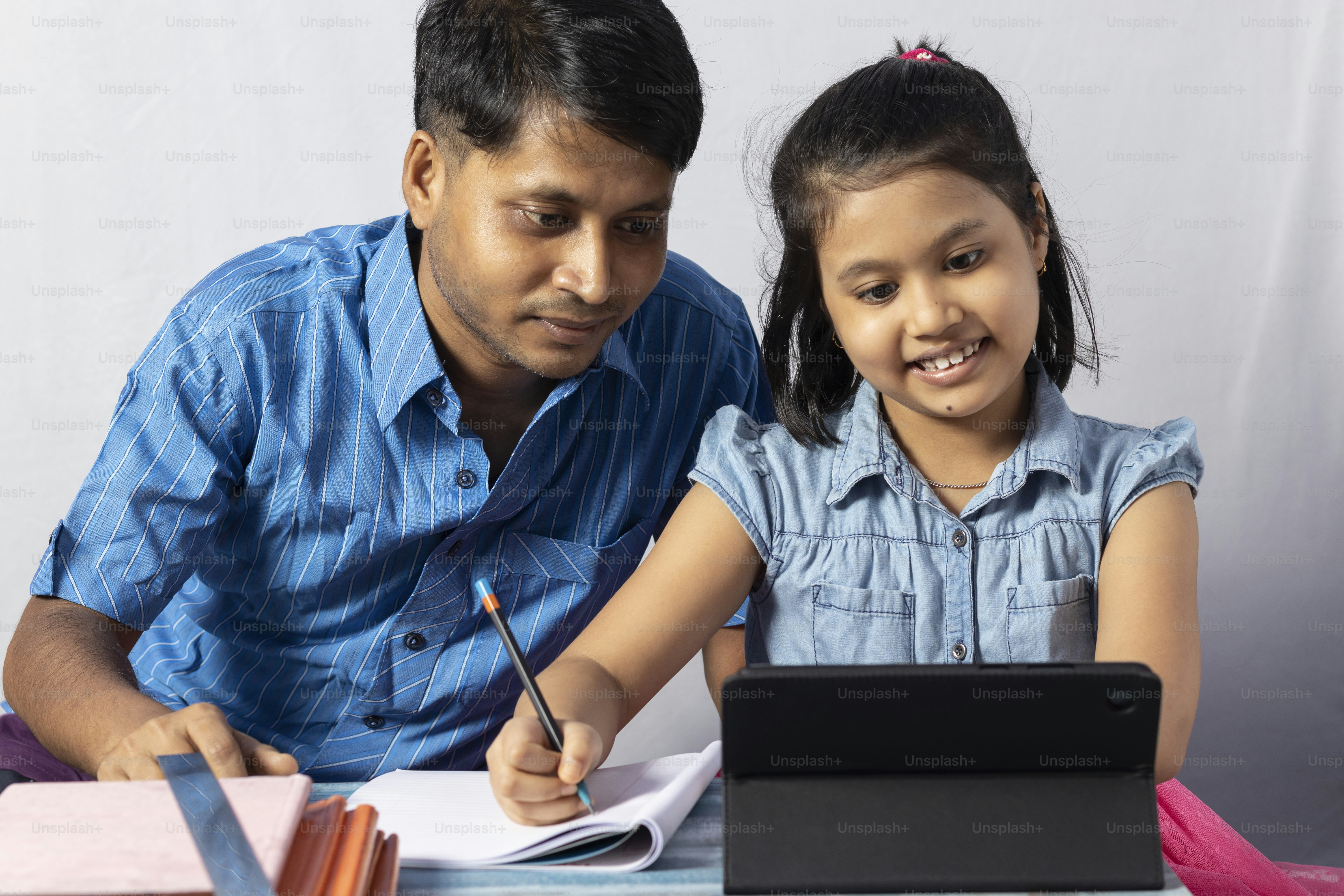 Una studentessa indiana che studia con il tablet oltre a suo padre, insegnante: concetto di insegnante privato