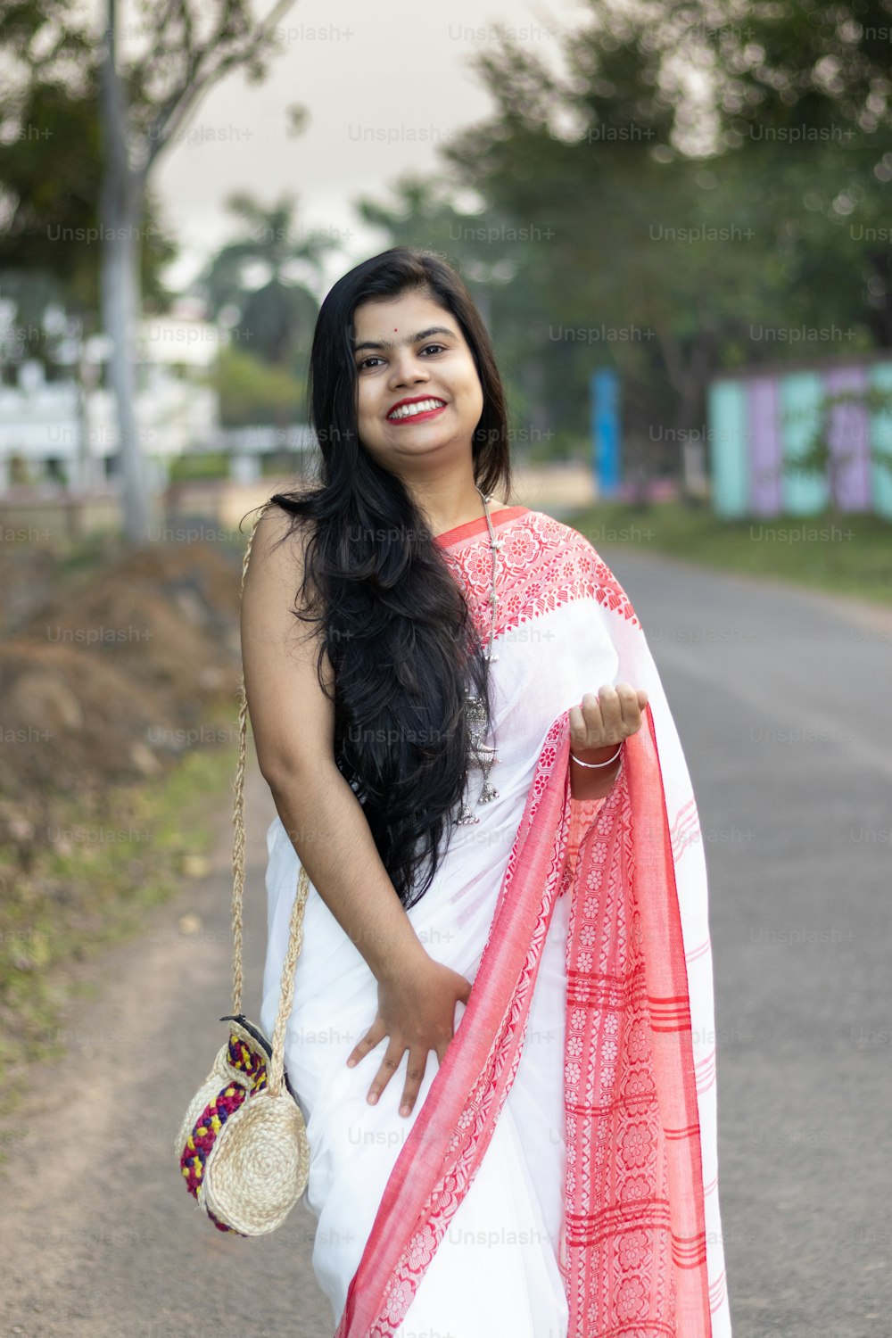 Una bella mujer india con sari rojo y cabello largo posando para la cámara en la carretera