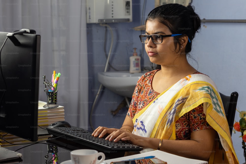 Mujer india en sari trabajando en computadora en casa, concepto de trabajo desde casa