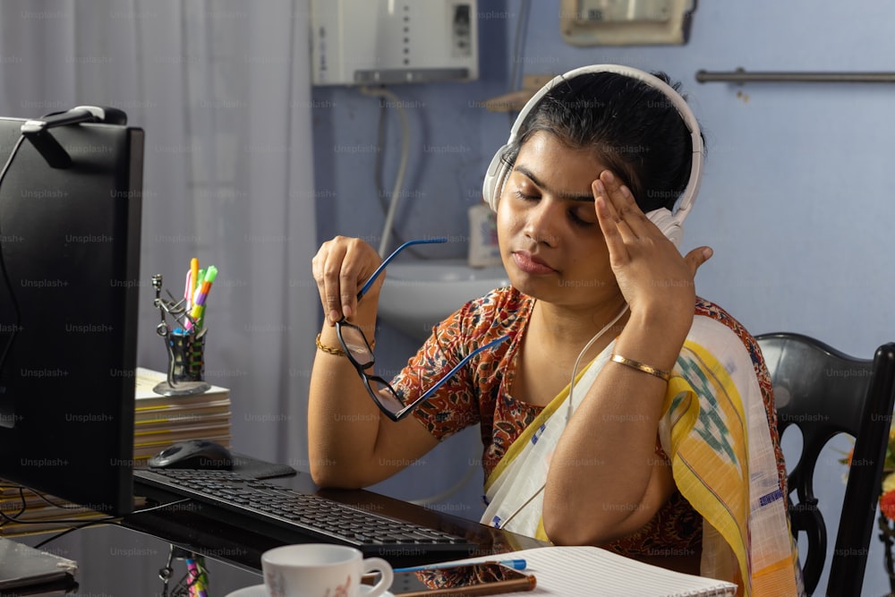 Mujer india en sari trabajando en la computadora desde casa y sintiendo dolor de cabeza, concepto de trabajo desde casa
