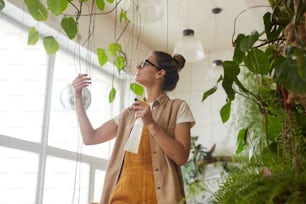 Young woman watering plants from splashing bottle in the garden