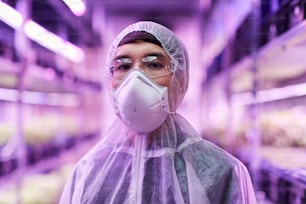 Portrait of Asian chemist in protective workwear and protective mask looking at camera