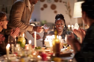 Jeune femme africaine heureuse de son gâteau d’anniversaire elle fête son anniversaire avec des amis à table à la maison