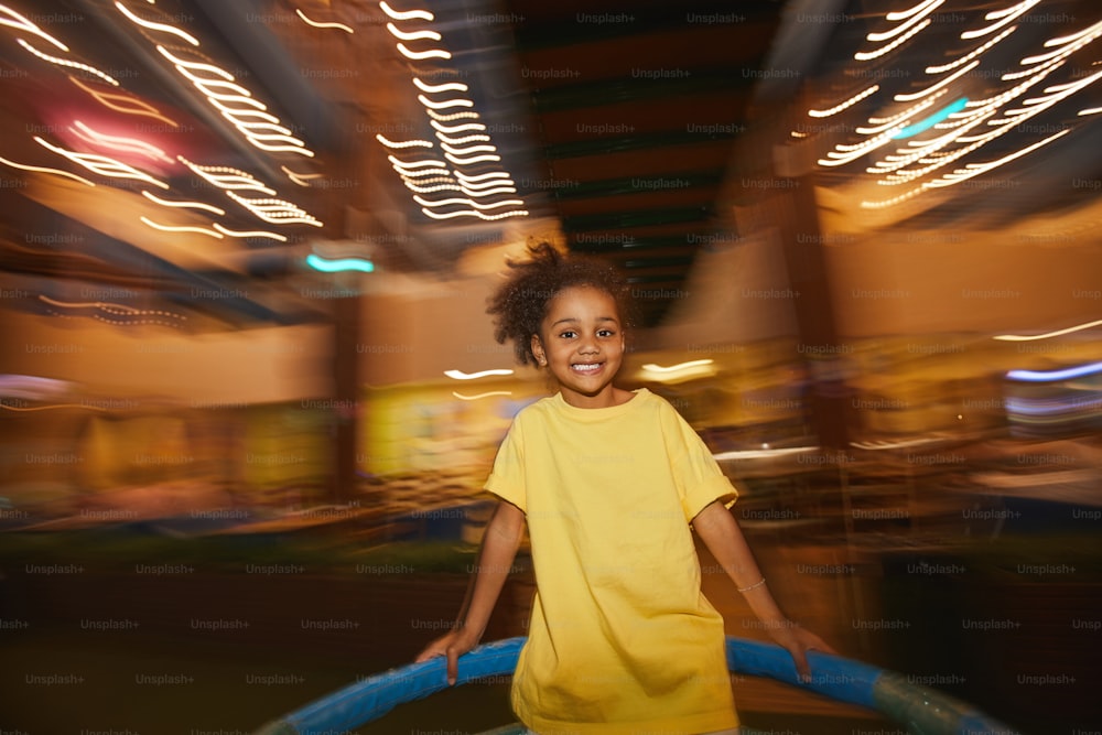Menina africana sorrindo para a câmera enquanto anda em um balanço no parque