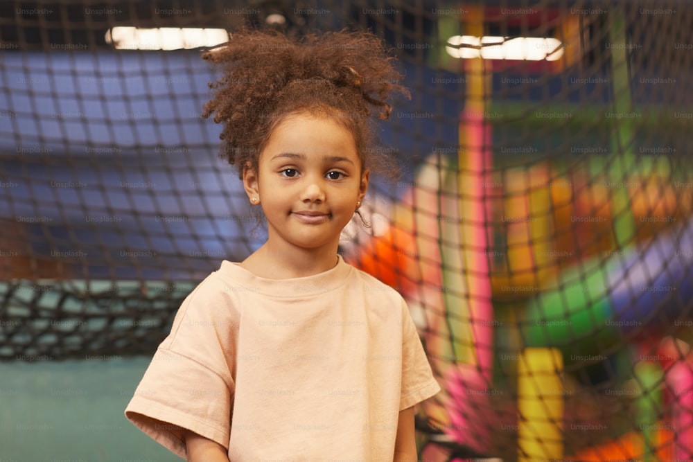 Portrait of African pretty child looking at camera standing in amusement park