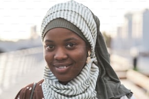 Close-up of African young woman in muslim clothes smiling at camera while standing outdoors