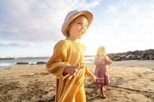 Lovely little sisters having fun at the beach, playing and smiling. Sunset summer time. A lot of copy space. Travel. Tourist.