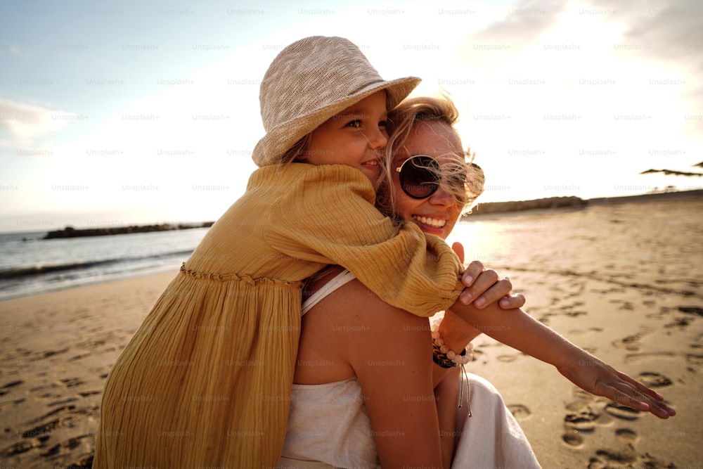 Happy mother with her little daughter having fun together on the beach, playing and hugging. Family summer vacations. Mother's day. Children's day. Real people emotions.
