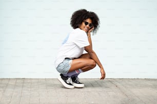 Happy young hipster woman with afro hairstyle and fashionable clothes posing outdoor. Sunny summer day. Good vibes only.