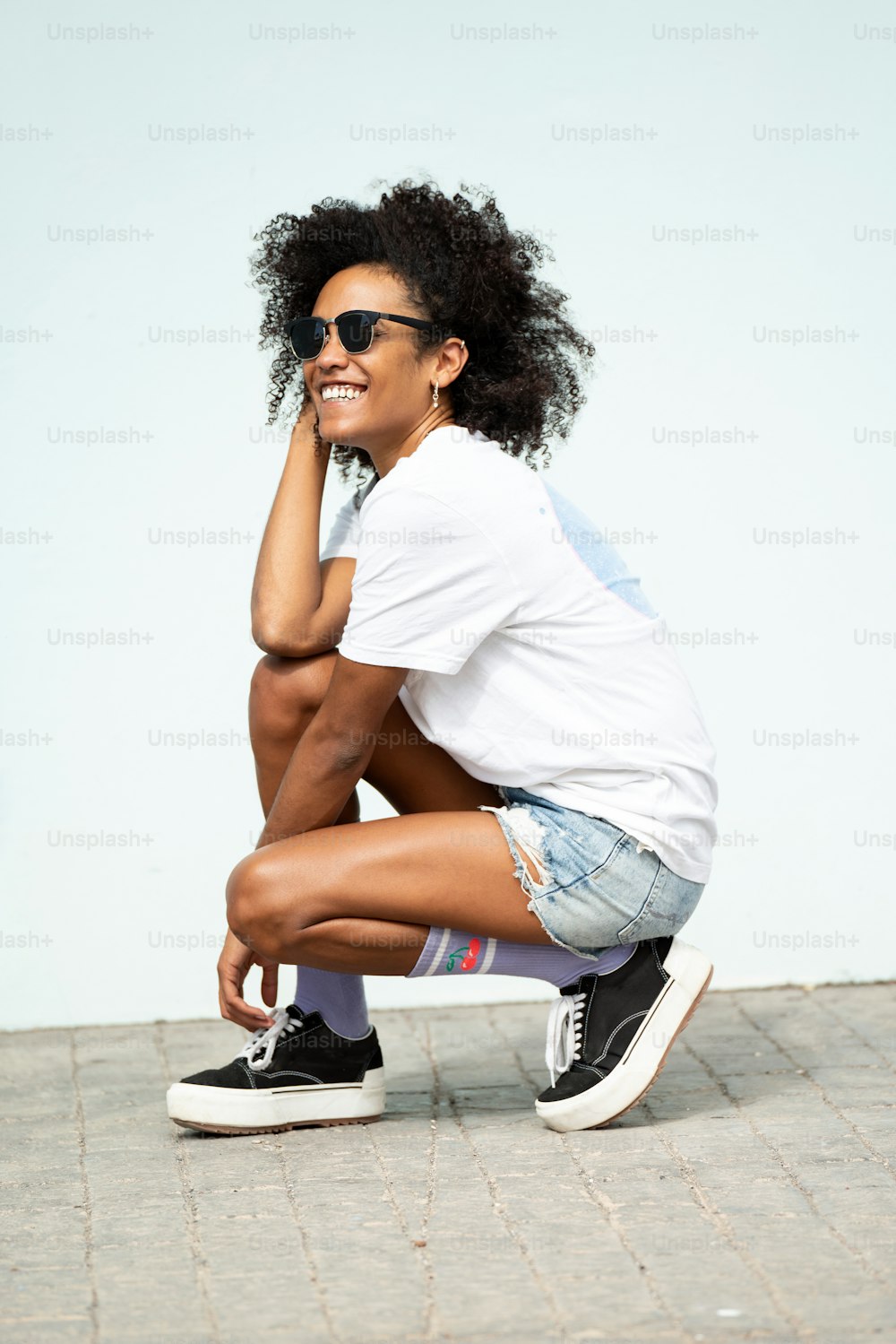 Glückliche junge Hipster-Frau mit Afro-Frisur und modischer Kleidung, die im Freien posiert. Sonniger Sommertag. Nur gute Stimmung.