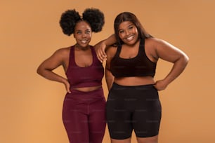 Active two plus size femal friends posing after training in fashionable sporty clothes ,smiling. Real people lifestyle. Gym, healthy lifestyle concept. Body acceptance.