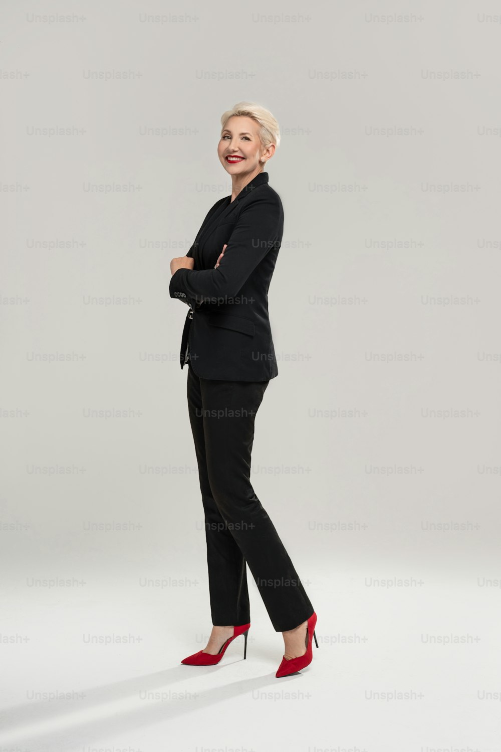 Successful businesswoman with short fashionable hairstyle and glamour makeup, looking at camera, standing. Full length photo. Copy space.