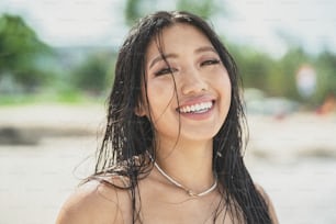 Chica isleña. Hermosa mujer asiática natural con cabello mojado y gran sonrisa dentada mirando a la cámara, disfrutando de un día soleado en la playa. Vibraciones tropicales. Viajero. Wanderlust. Retrato de belleza.