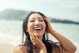 Retrato de una hermosa joven asiática con una increíble sonrisa dentada. Chica con el pelo mojado disfrutando de un día soleado en la playa. Concepto de estilo de vida feliz de vacaciones. Emociones de personas reales. Viajero.