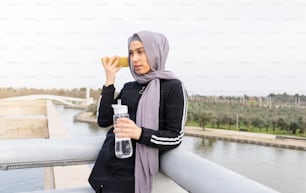 woman with hijab thirsty in the park after sport - muslim female athlete concept -