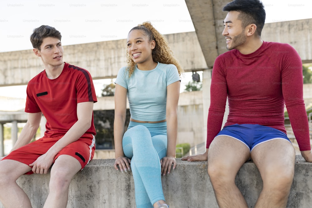 A young group of multi-ethnic friends have a conversation outdoors after fitness training curly-haired Hispanic woman talking to her friends.