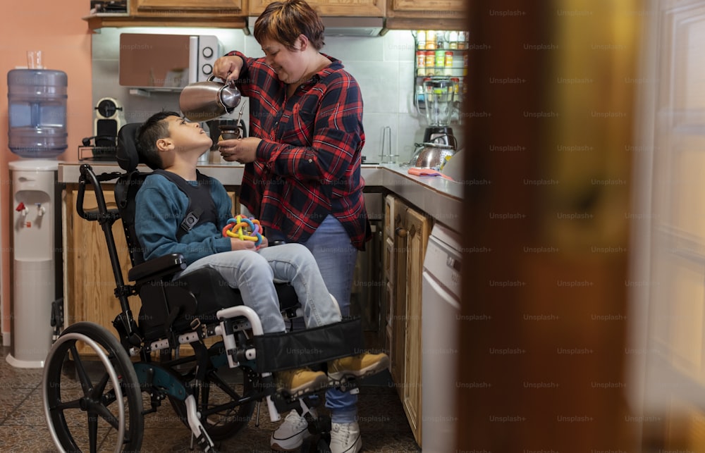 Madre con hijo que tiene una discapacidad en la cocina del hogar