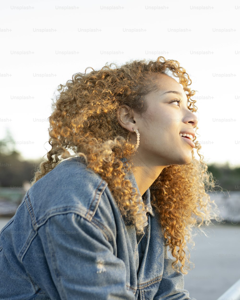 pretty woman with curly hair, profile picture outdoors, thinking, observing