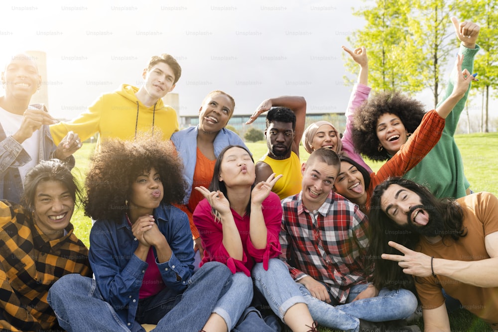 Diverse young people having fun outdoors laughing together making funny faces joking for selfie. Multiracial group of diverse sexual orientations - focus on Asian women -.