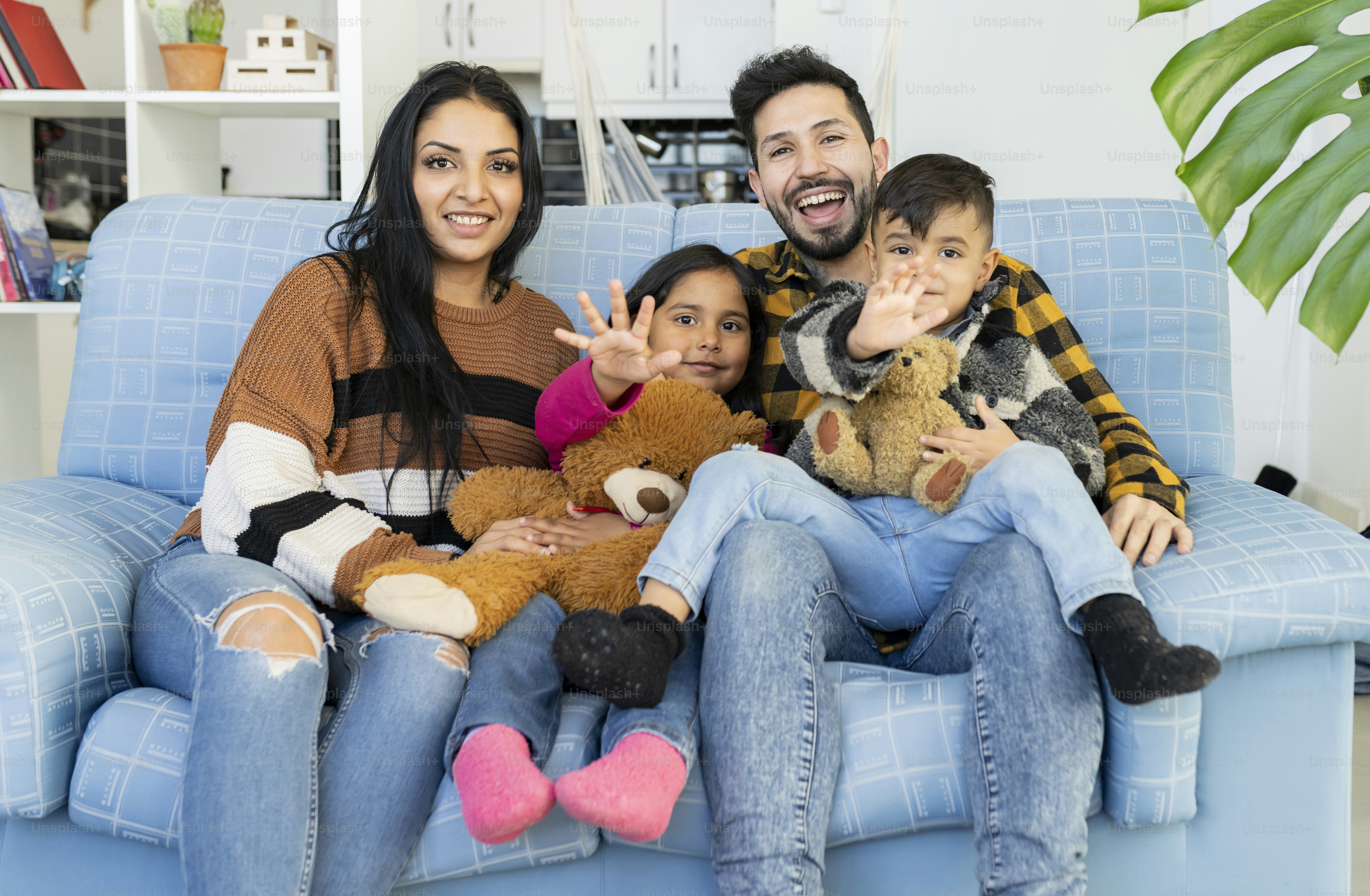 Concepto de Familia y Pueblo Hispano - Retrato de padre, madre, hijo e hija felices agitando las manos en casa