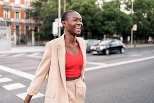Laughing elegant young adult woman with short hair crossing the street in the city.