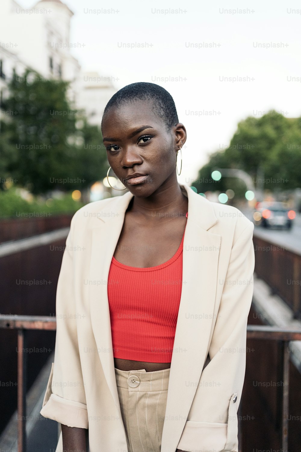 Portrait of an african american young woman with short hair standing and looking at camera on a footbridge in the city