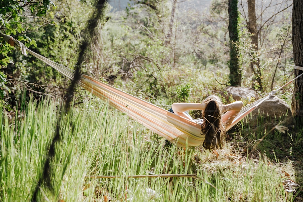 a woman laying in a hammock in a forest