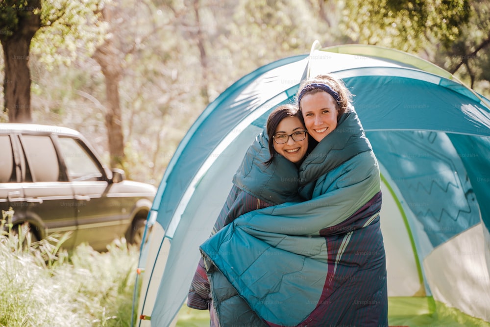 a couple of women hugging each other in front of a tent