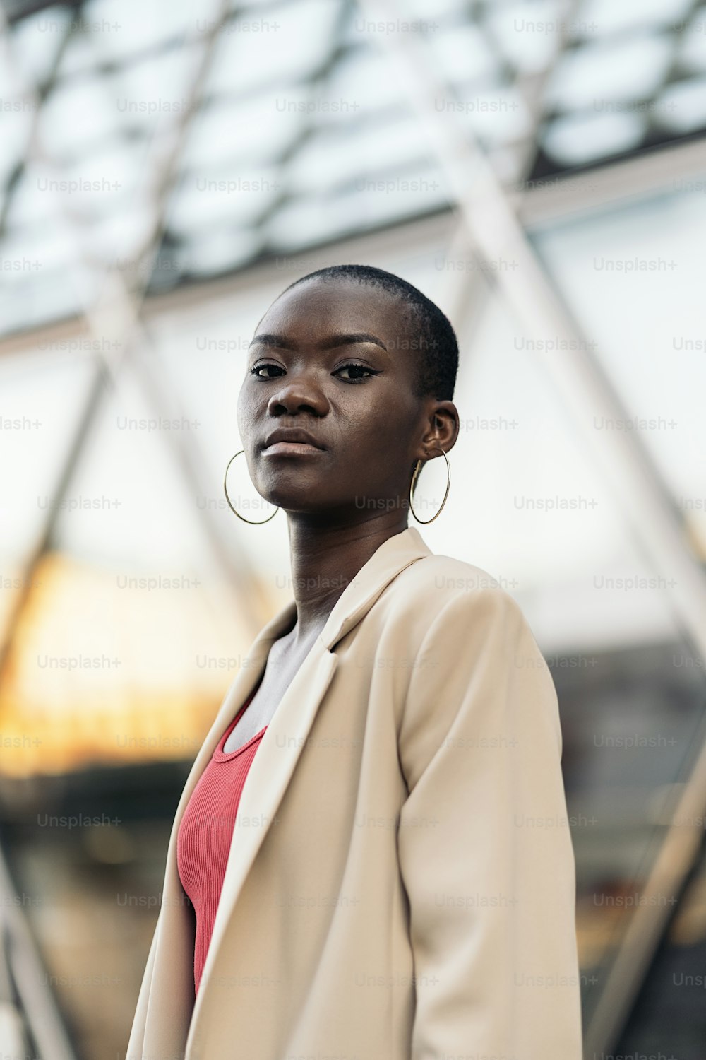 Vista de baixo ângulo de uma mulher jovem adulta afro-americana elegante com cabelo curto em pé e olhando para a câmera na cidade