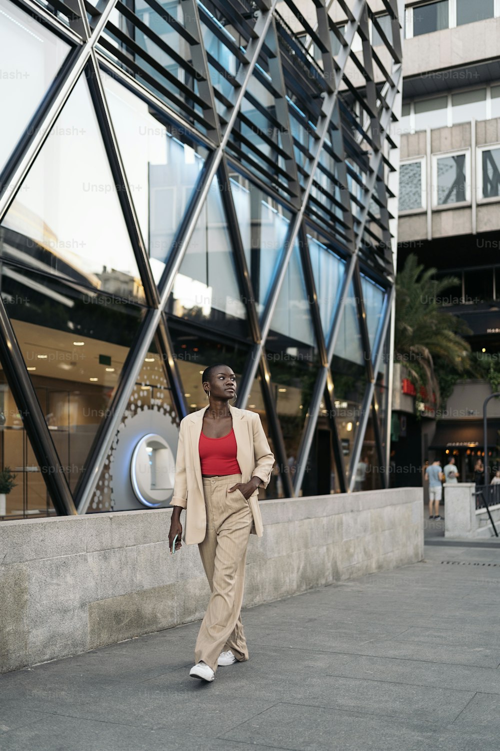 Stylish young african american woman with short hair walking on the city looking away while holding her phone.