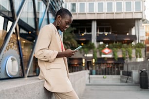 Vista lateral recortada de una mujer adulta joven afroamericana con cabello corto usando el teléfono en la ciudad